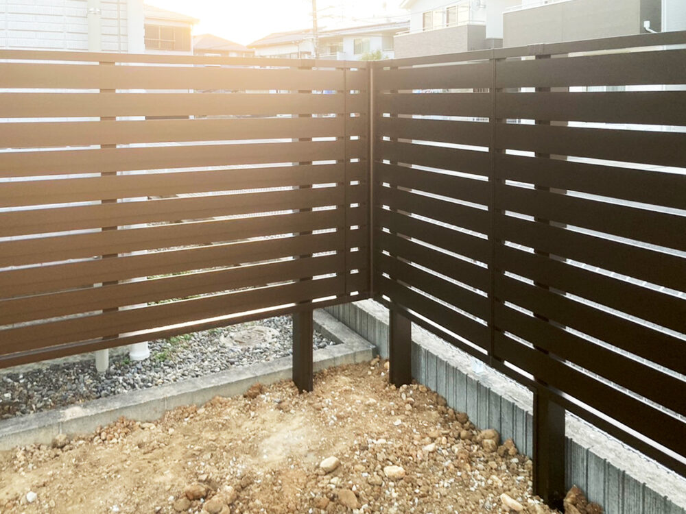 住宅境界に設置した木調フェンスのコーナー納まり。視線を遮りながら開放感も確保した外構デザイン。